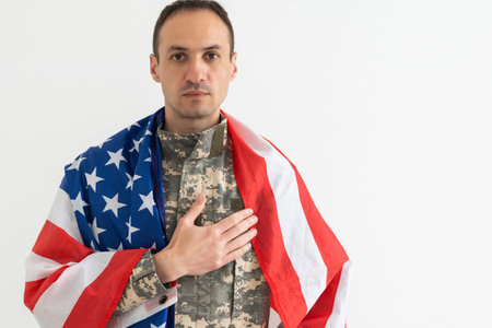 american military soldier holding flag. male officer in camouflage uniform. Concept of military, army.の写真素材