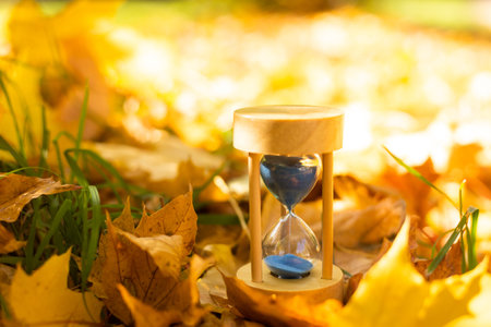 hourglass in fallen autumn leaves.の写真素材