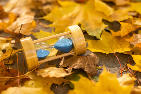 hourglass in fallen autumn leaves.の写真素材