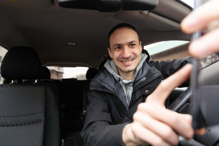 Handsome young man in denim shirt pressing touchscreen on car multimedia panel, switching shifting...