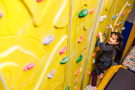 little girl climbing a rock wall indoor.の写真素材
