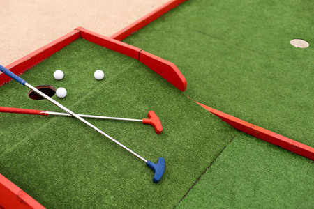 colorful golf putters with golf balls on synthetic grass