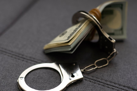Banknotes dollars money and handcuffs isolated on black background. Dark image for corruption or fraud. money laundering conceptの写真素材