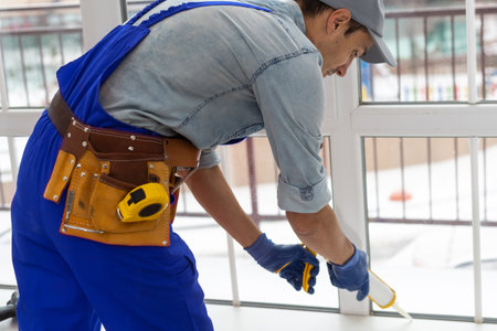 Construction worker repairing plastic window with screwdriver indoors, closeupの写真素材