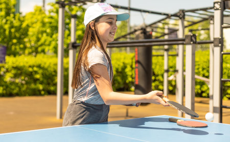 Little girl playing table tennis in parkの写真素材