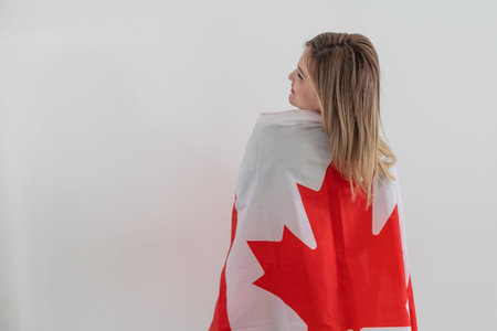 Happy young woman with the flag of Canada on a light white background. Portraits Canadian student female.の写真素材