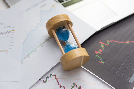 Hourglass standing on table with sand trickling, man working with graphs, data, stock footage