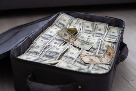 an old black suitcase with an open lid full of one hundred dollar bills. Corruptionの写真素材