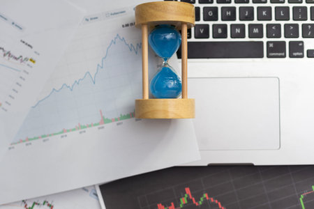 Clock alarm with stock graph chart in laptop screen background.Time,stock market,business success...
