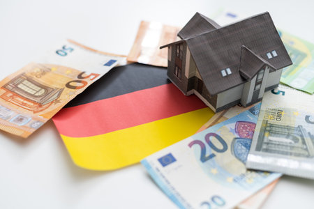 Real estate concept. On the flag of Germany there is a model of a wooden house with the inscription - INTEREST PRIME RATEの写真素材