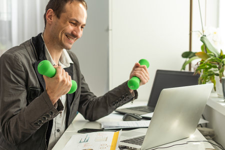 Victory concept. Successful cheerful lucky caucasian bearded businessman, ceo company, manager, sits at work desk in the office, gesturing with fistsの写真素材