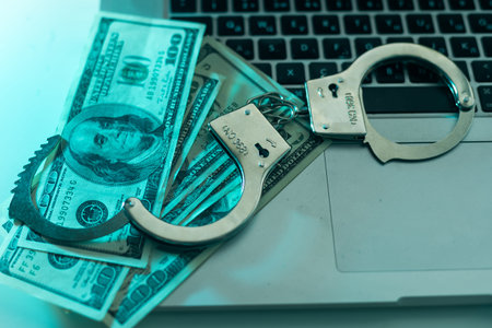 Pair of handcuffs closeup on dollar banknotes background. Corruption problem in the world