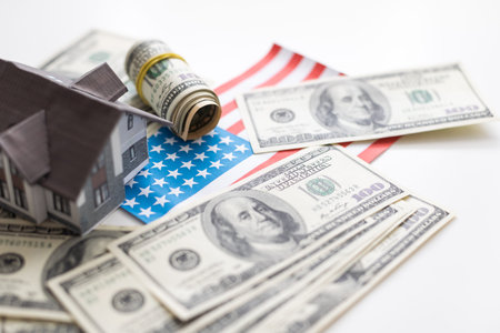 A toy house made of wood with a roof costs money, on a hundred-dollar bill. Concept: mortgage, purchase, sale of real estate, rental housing.の写真素材