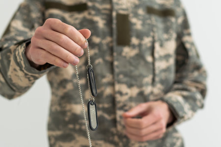 A Ukrainian military man is holding a military token with a trident, the emblem of the national coat of arms of Ukraine. War in Ukraine.の写真素材