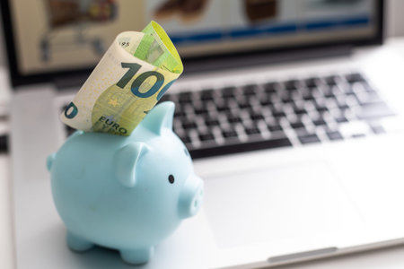 inserting euro coins in a piggy bankの写真素材