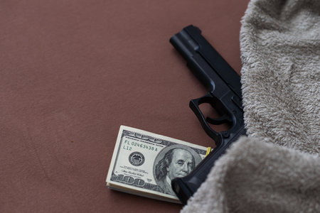 Pile of US dollar cash and a black pistol gun. Seen from above.の写真素材