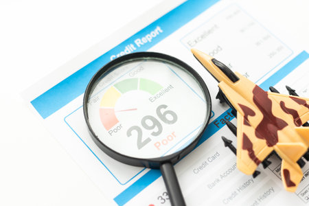 Credit Report text on paper sheet with magnifying glass on chart, dice, spectacles, pen, laptop and blue and yellow push pin on wooden table - business, banking, finance and investment conceptの写真素材