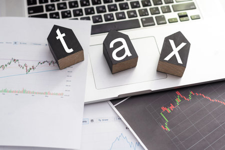 Tax text in wooden cubes and tax or vat form documents to complete Individual income tax return form...