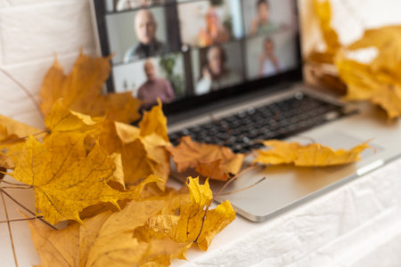 dry autumn leaves and laptop video chatの写真素材
