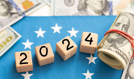 2024 inscription on wooden cubes on the texture of us dollars and euro banknotes
