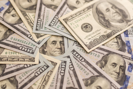 Many hundred dollar bills on wooden table background texture. bundles of money scattered on the...