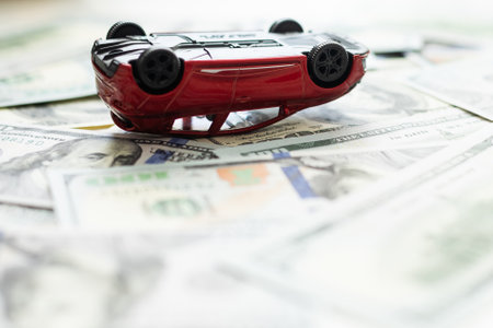 Small, toy, red car had accident on one hundred dollar banknotes, isolated on white background.の写真素材