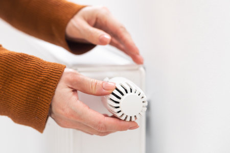 Woman holding temperature knob of heating radiatorの写真素材