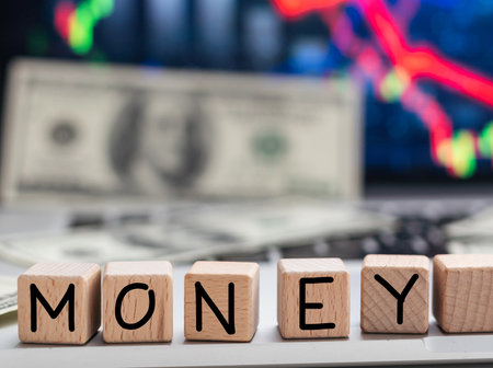 MONEY the word on wooden cubes, cubes stand on a reflective surface, in the background is a business diagram. Business and finance conceptの写真素材