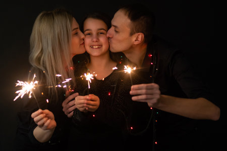 Young family with sparklers at Christmas time on a black backgroundの写真素材