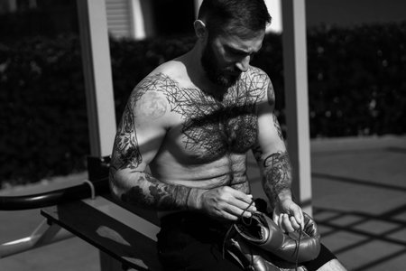 The young guy trains in the park on the street exercise machine