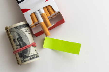 Cigarettes wrapped in 100 dollar bills on a gray background. The concept of a constant increase in the price of cigarettes.の写真素材