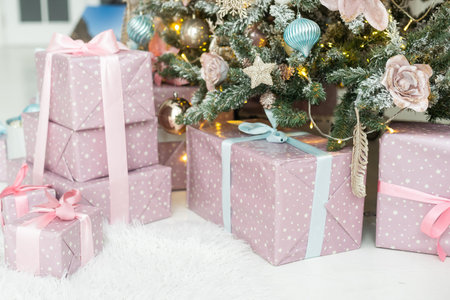 Beautiful Christmas gifts under fir tree on floor in room.