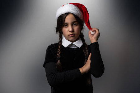 Portrait of little girl with Wednesday Addams costume. Wednesday girl with a Santa hat