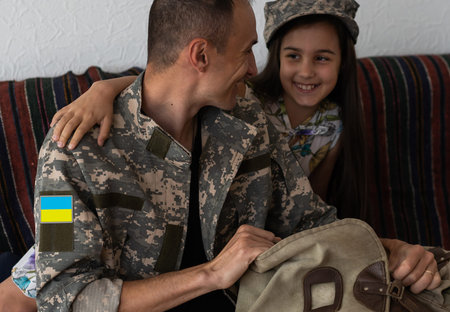 Soldier in Ukrainian military uniform hugging his daughter. Family reunion