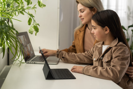 Teen girl distance learning virtual distance online class on video call virtual lesson with mother,...