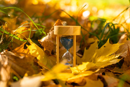 hourglass in fallen autumn leaves.