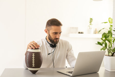 Troubled businessman thinking about work playing with football handheld in officeの写真素材