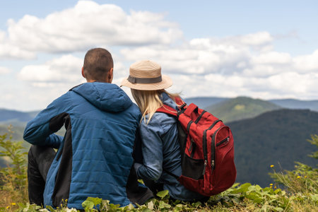 Hikers with backpacks relaxing on top of a mountain and enjoying the viewの写真素材
