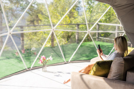 Shot of a woman using a smartphone while relaxing at homeの写真素材