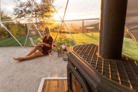 Transparent bubble tent at glamping, Lush forest around and interior. Woman with laptopの写真素材