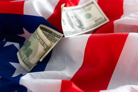 US flag. Stock market prices chart under the flag. Rolled one hundred us dollar bill lying on the...