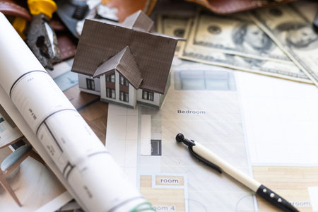 Model house, calculator, cash money and paperwork on a desk: real estate, home loan and investments...