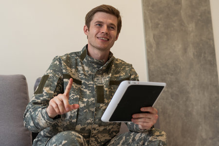 Happy young soldier holding a computer tablet