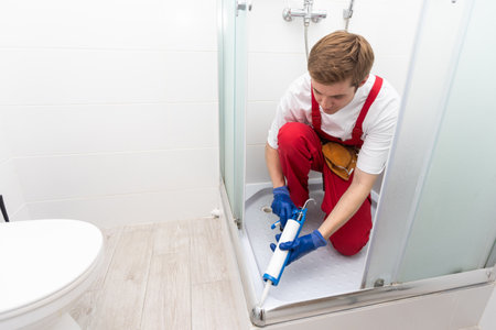 Young man repairing door of shower cabin in bathroom.の写真素材