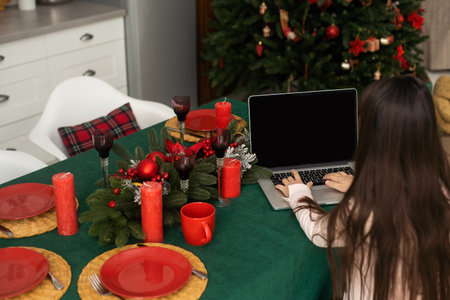 Teenage girl with gifts and laptop near the Christmas tree. Living room interior with Christmas tree and decorations. New Year. Gift giving.の写真素材