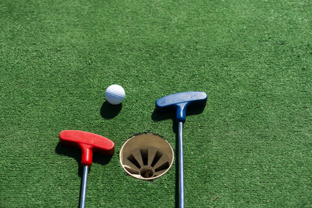Close-up of miniature golf hole with bat and ball