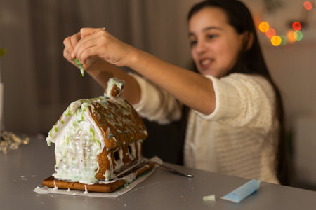 A girl plays with a gingerbread house for traditional Christmas decorationの写真素材