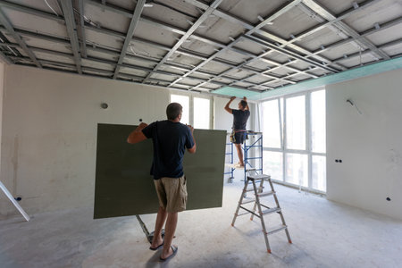 Workers fitting panel into frame of ceiling.の写真素材