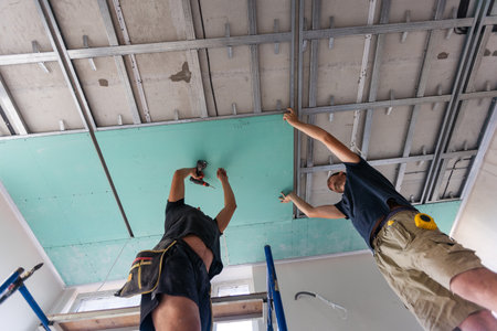 Workers fitting panel into frame of ceiling.の写真素材