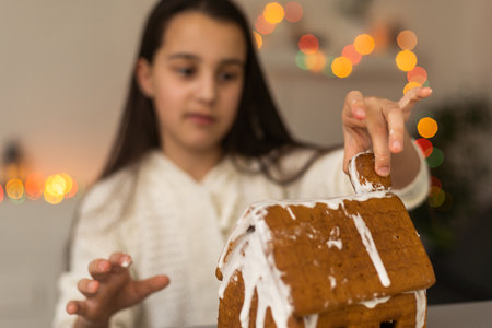 Little girl decorating gingerbread house for Christmasの写真素材